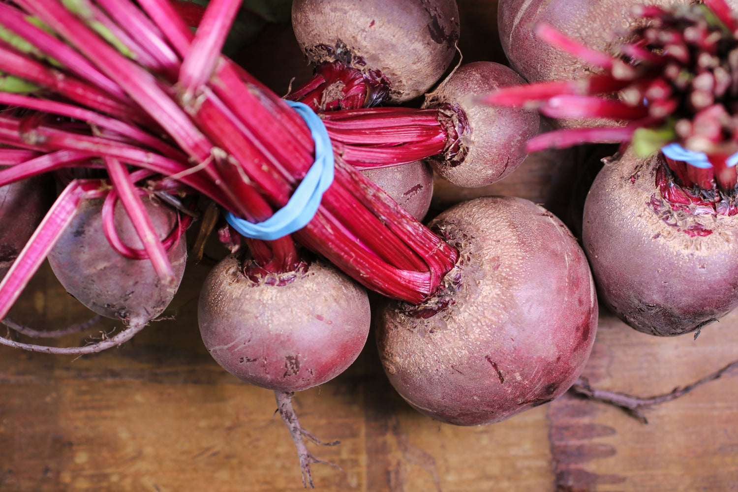 Bunch of beets with stems attached on a wooden surface