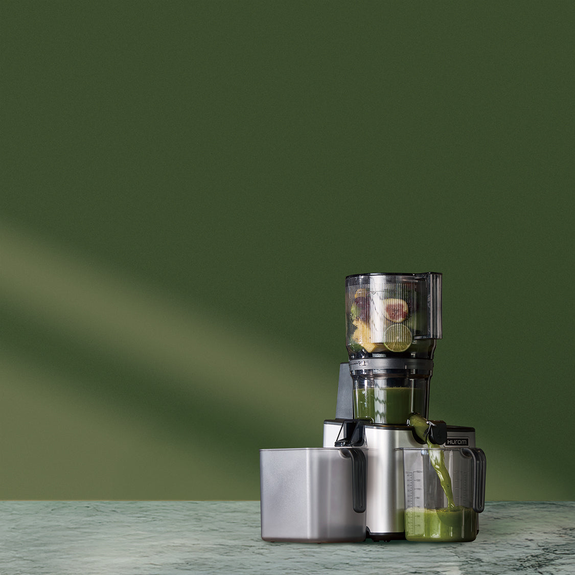 Juicer with green juice on a green background