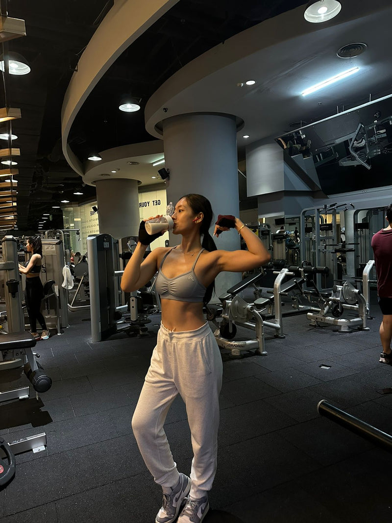 Woman exercising in a gym with equipment and people in the background