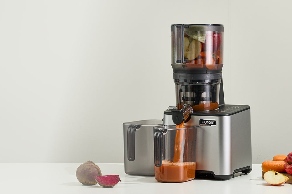 Juicer with fruits and vegetables on a white surface CP50