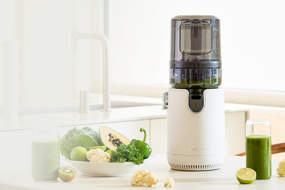 Juicer with green juice and fruits on a kitchen counter E50ST