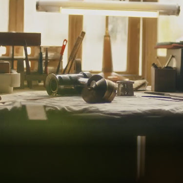 A nostalgic workshop scene featuring an engineer's workbench covered with technical blueprints, metal tools, and juicer components under warm lighting. The text "Our Story" is displayed in the bottom left, symbolizing Hurom's heritage and craftsmanship.