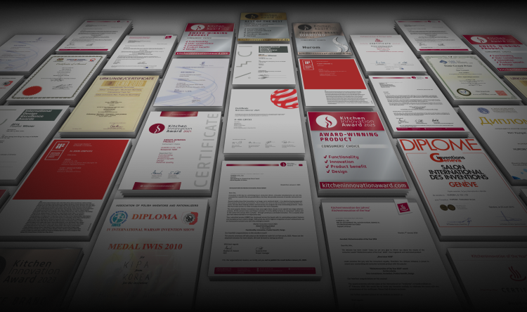 Zahlreiche internationale Design und Erfinderurkunden, auf dem Boden ausgebreitet. Die Überschrift lautet: Zahlreiche internationale Auszeichnungen bestätigen den wahren Wert des Erstseins, mit Verweis auf die drei bedeutendsten internationalen Erfinderpreise und den Kitchen Innovation Award in neun Jahren in Folge.